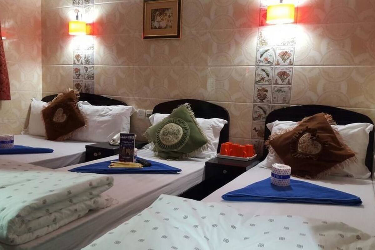 Une chambre d’hôtel avec deux lits, chacun équipé d’un oreiller, d’une petite table avec une tasse et d’une télécommande.