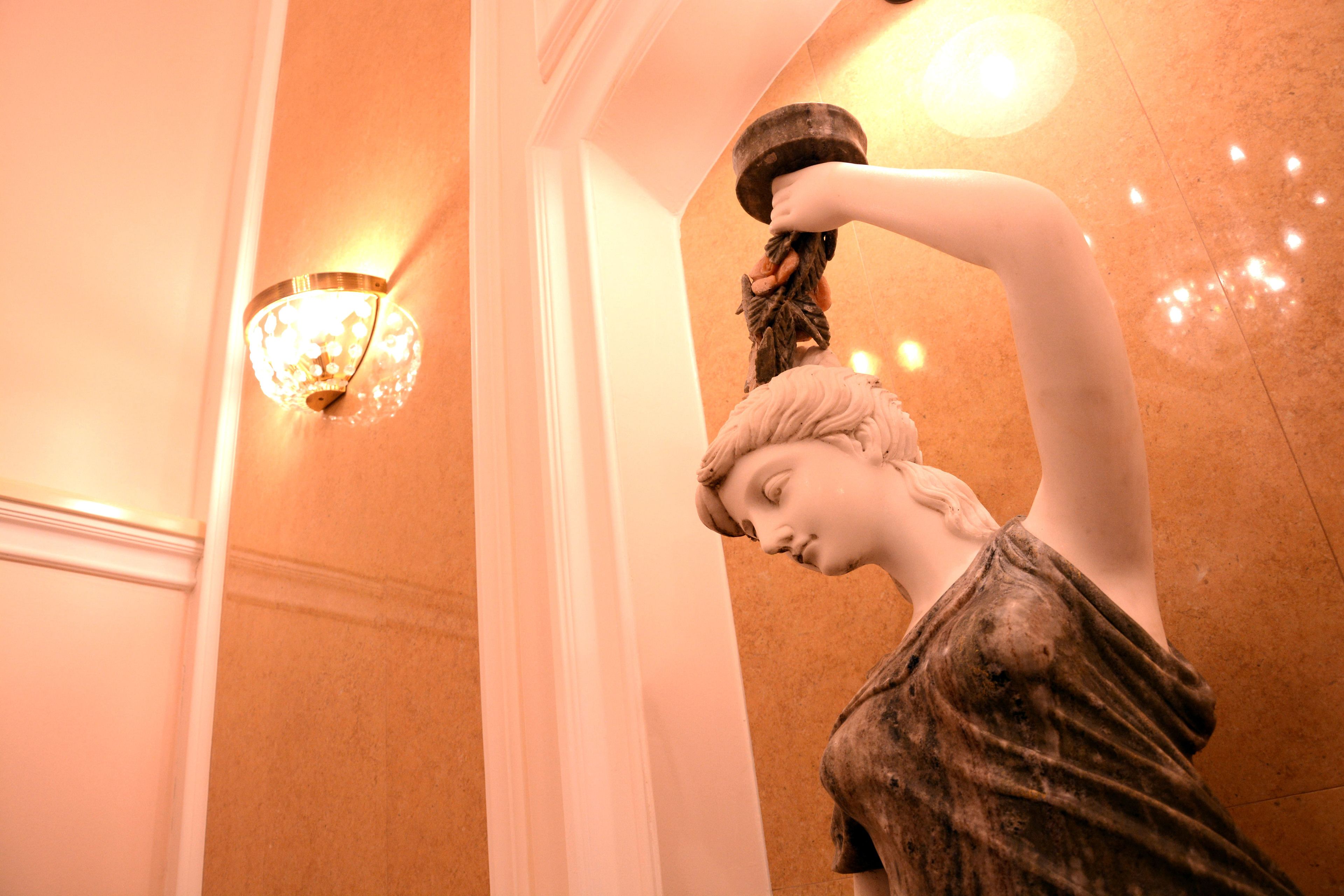 A statue in a lobby with a wall-mounted light fixture.
