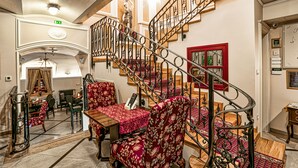 A grand staircase with ornate metal railings, a red-framed window, and a statue above. - Arbia Dorka Heritage Palace (Varazdin)