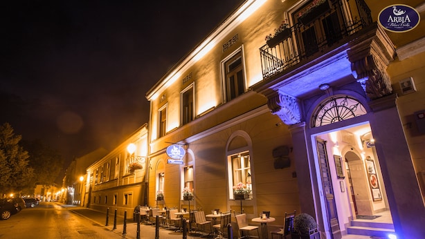 A building with outdoor seating, a sign for 'Arbia Palace Hotel', and a well-lit entrance. - Arbia Dorka Heritage Palace (Varazdin)