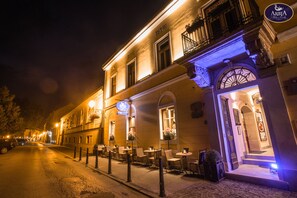Un edificio con mesas al aire libre, un letrero que dice 'Arbia Palace Hotel' y una entrada bien iluminada.