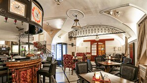 A restaurant interior with a bar, dining tables, chairs, and a staircase leading to an upper level. - Arbia Dorka Heritage Palace (Varazdin)
