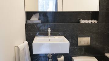 A modern bathroom with a white sink, a toilet, and a mirror above the sink.