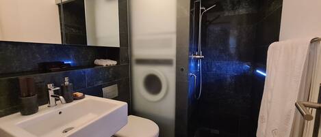 A modern bathroom with a white sink, toilet, and a glass-enclosed shower area.
