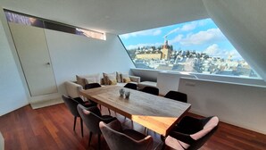A dining area with a wooden table and chairs, a view of a cityscape through a skylight, and a white door. - Lucerne Lake View Apartments (Lucerne)