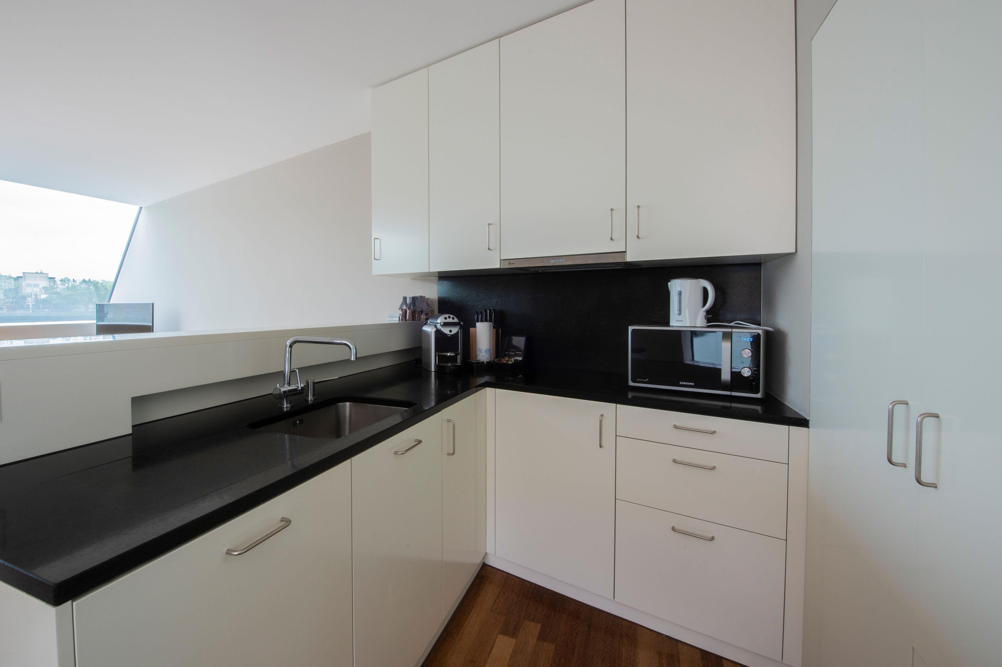 A modern kitchen with white cabinets, black countertops, and stainless steel appliances.