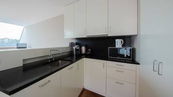 A modern kitchen with white cabinets, black countertops, and stainless steel appliances.