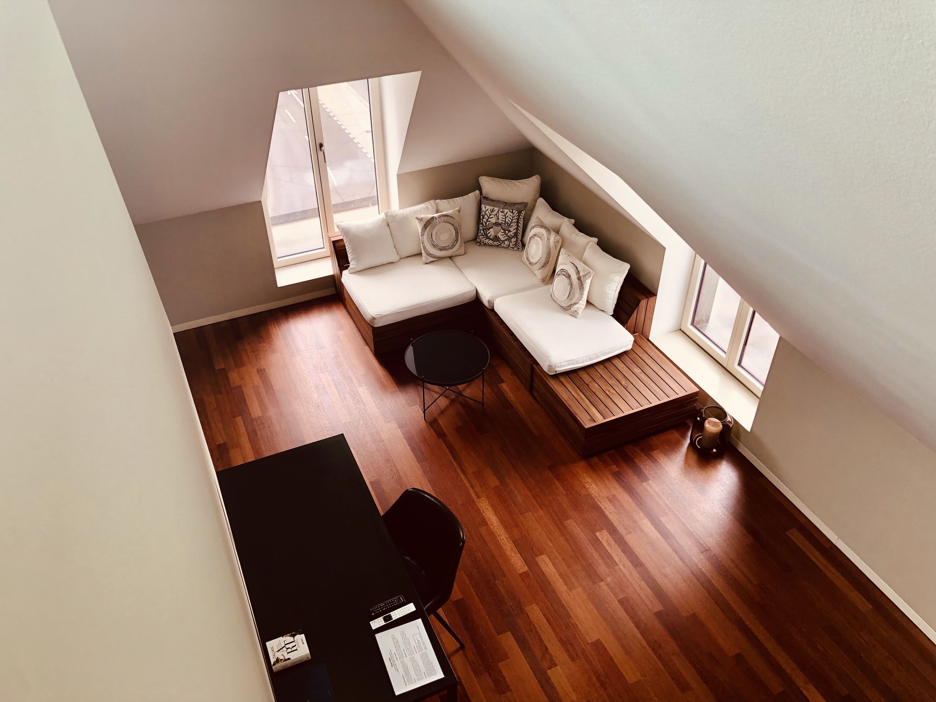Une pièce de style « loft » avec un canapé intégré, une petite table ronde et une chaise noire.
