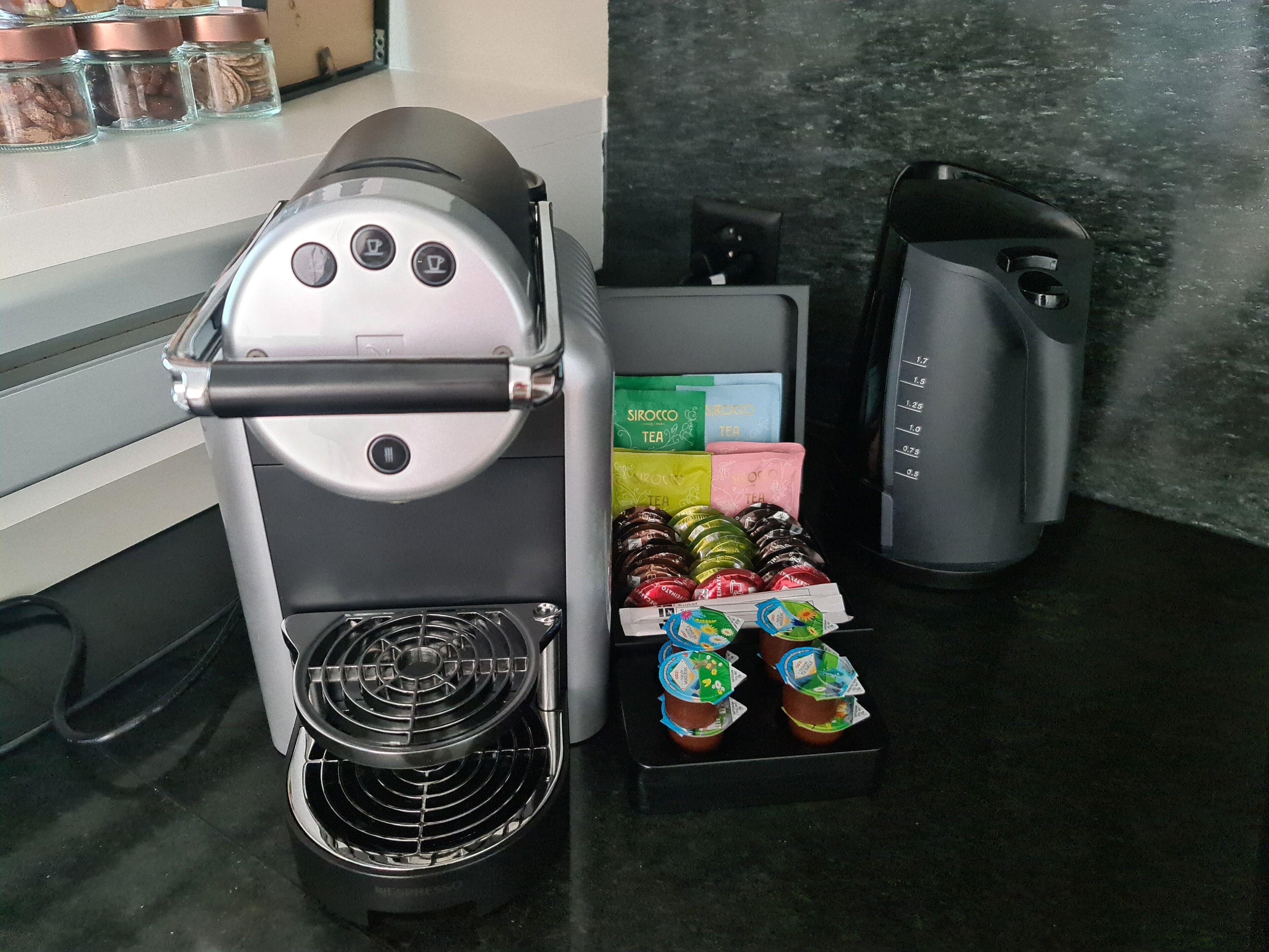 A coffee machine with a drip tray and a box of assorted tea bags.