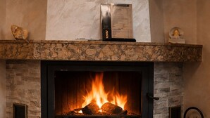 Una chimenea con leña, una vela y un televisor montado encima.