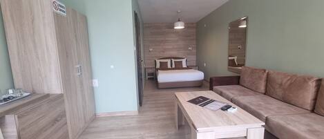 Un dormitorio moderno con un armario de madera, una cama con cabecera, una mesita de noche, un sofá y un espejo en la pared.