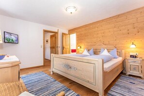 Un dormitorio con cabecera de madera, una mesita de noche con lámpara y cama con ropa de cama azul y blanca.