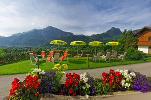 A garden with colorful flowers, outdoor seating, and a mountain backdrop. - Leitnerhof (Bad Reichenhall)