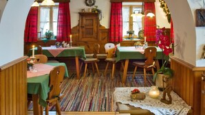 A cozy dining area with wooden furniture, a colorful striped rug, and a festive arch decorated with lights and greenery. - Leitnerhof (Bad Reichenhall)
