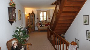 A cozy living room with a staircase, a wooden cabinet, a sofa, and a chair. - Leitnerhof (Bad Reichenhall)
