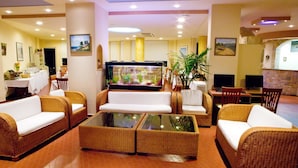 Un hall d'entrée avec des canapés en osier, une table basse en verre et un aquarium.