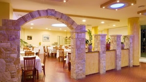 Un restaurant doté d’arches en pierre, de tables et de chaises en bois.