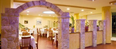 A restaurant with stone arches, wooden tables, and chairs.