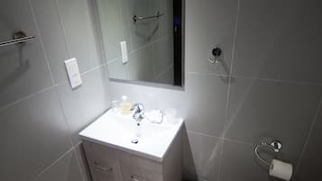 A modern bathroom with a white sink, mirror, and toilet.