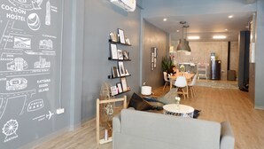 A modern hostel interior with a map on the wall, a dining area, and a kitchenette. - The Cocoon Hostel (Bangkok)