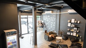 A modern lounge area with a seating area, a refreshment machine, and a chalkboard wall with maps and text. - The Cocoon Hostel (Bangkok)