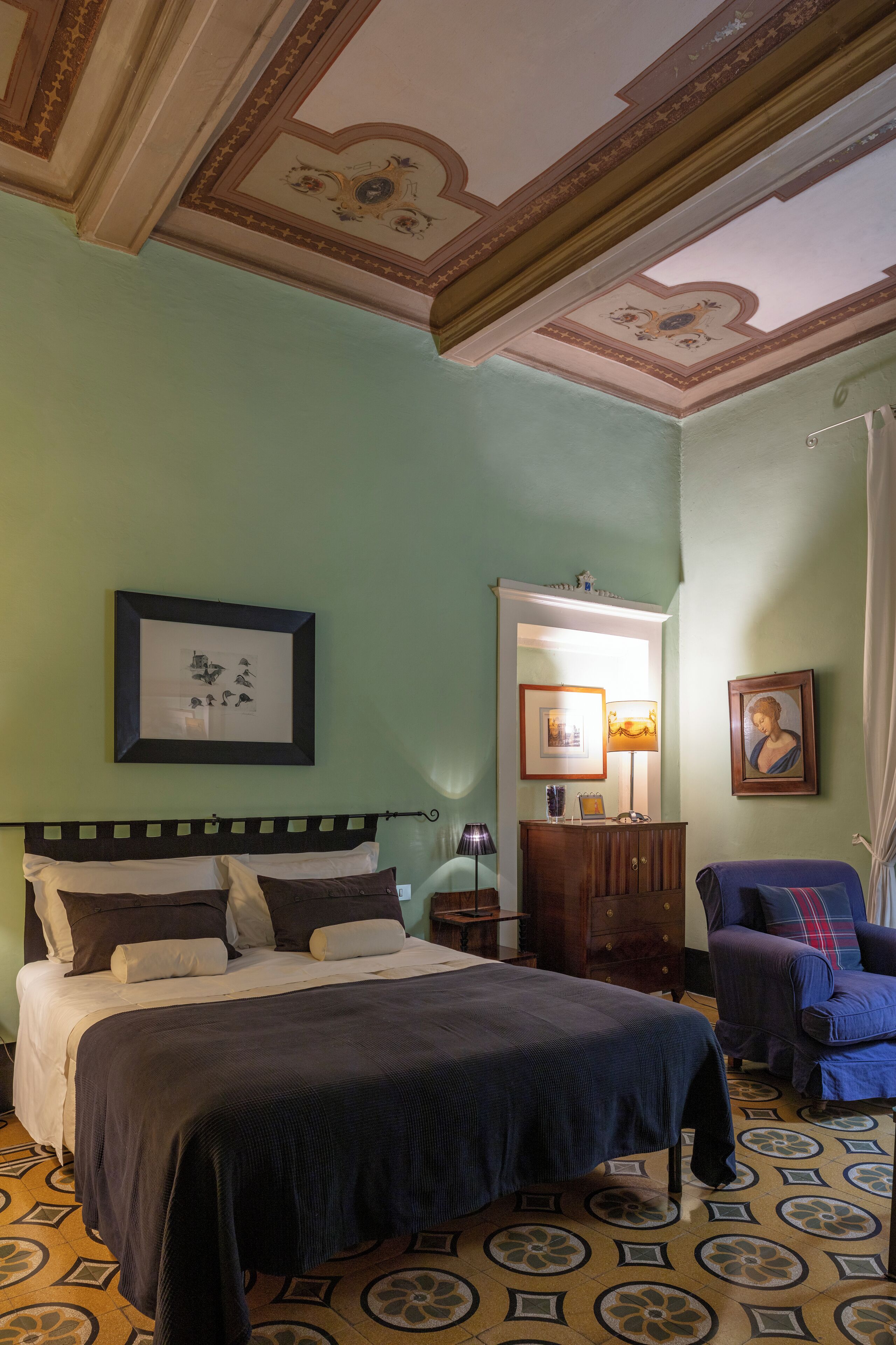 A bedroom with a bed, a dresser, a chair, and a mirror.