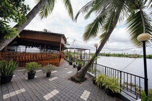 A waterfront restaurant with outdoor seating, a wooden deck, and a view of the water.