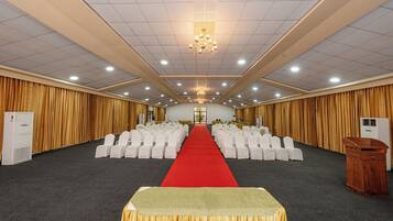 A conference room with rows of white chairs, a red carpet, and a chandelier.