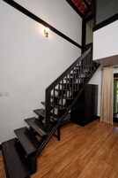 A staircase with a black handrail and wooden steps leading to a landing.