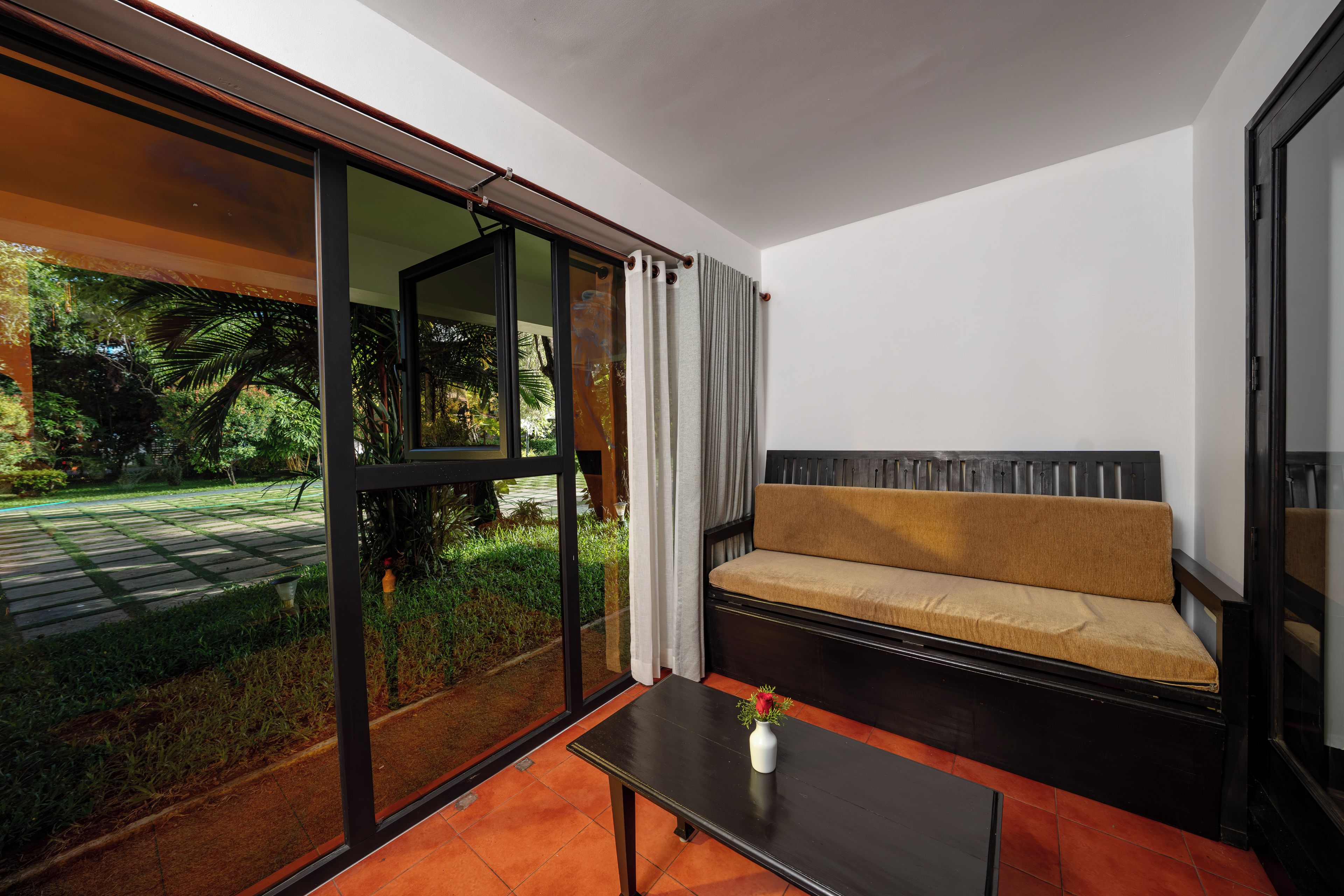 Un interior moderno con un sofá, una mesa y vistas a un jardín a través de amplios ventanales.