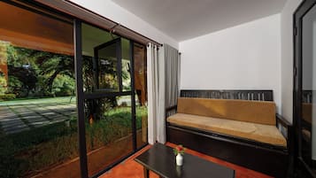 Un interior moderno con un sofá, una mesa y vistas a un jardín a través de amplios ventanales.