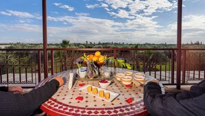 Una mesa con vistas al campo, un cuenco de fruta y un plato de pan.