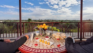 Una mesa con vistas al campo, un cuenco de fruta y un plato de pan.