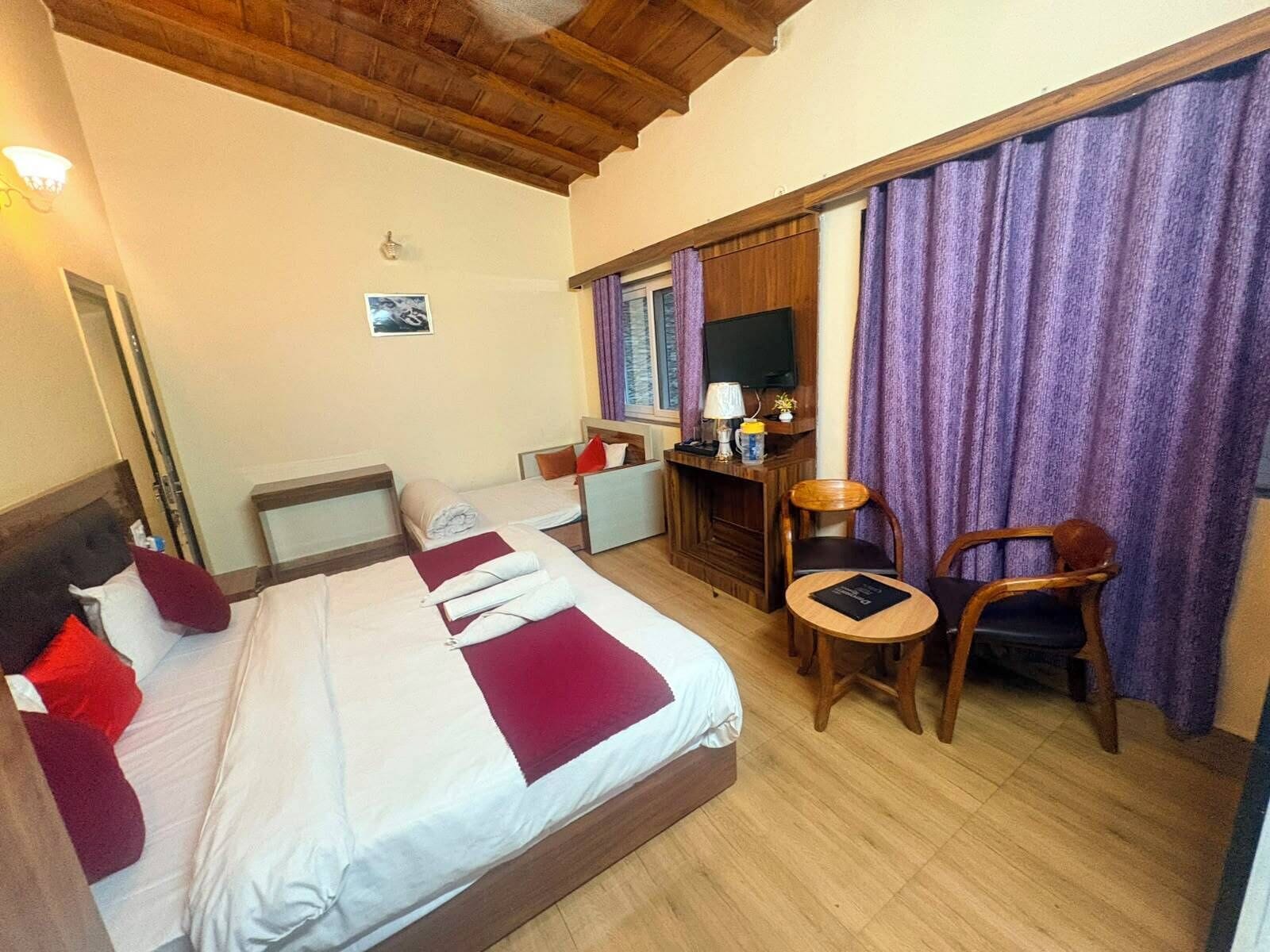 Quarto de hotel com uma cama, uma escrivaninha, uma cadeira e uma televisão.