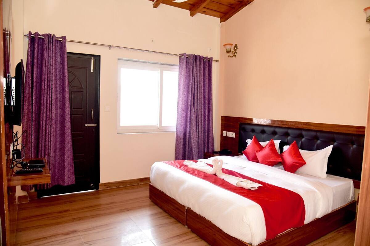 Ein Schlafzimmer mit einem hölzernen Bett, roter und weißer Bettwäsche, violetten Vorhängen, einem Holzboden und einem Fenster.