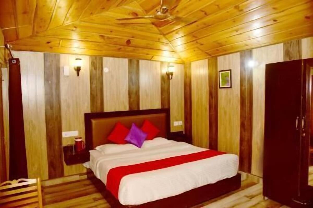 Ein Zimmer mit Holzwänden, einem Bett, einem Nachttisch, einem Kleiderschrank und einem Deckenventilator.