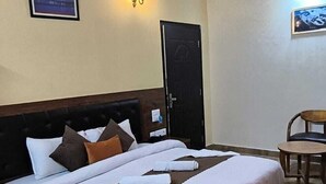 Ein Hotelzimmer mit einem großen Bett, einem Holzkopfteil, einem Schreibtisch mit Stuhl und einer Tür.
