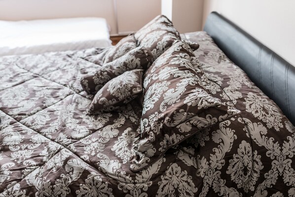 A bed with a patterned bedspread and pillows.