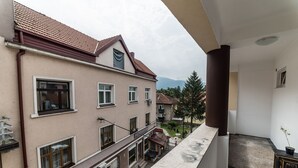 A multi-story building with a balcony, a tiled roof, and a view of a mountain. - Suite Donna (Bihac)