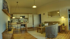 A cozy living room with a sofa, a dining table, and a kitchen area with cabinets and a refrigerator. - Fewos am Hafen (Sellin)