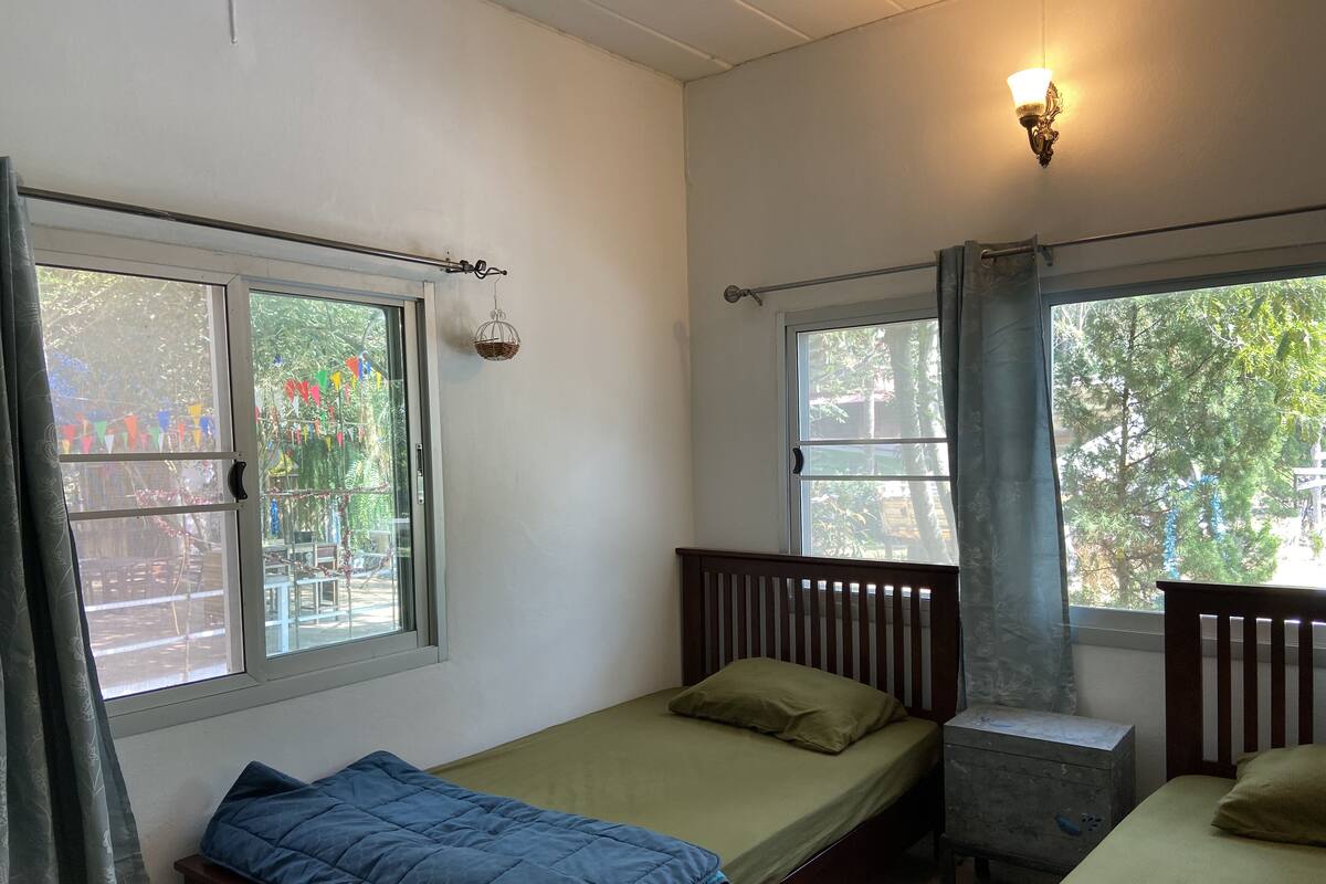A room with two single beds, a small table, and a window with curtains.