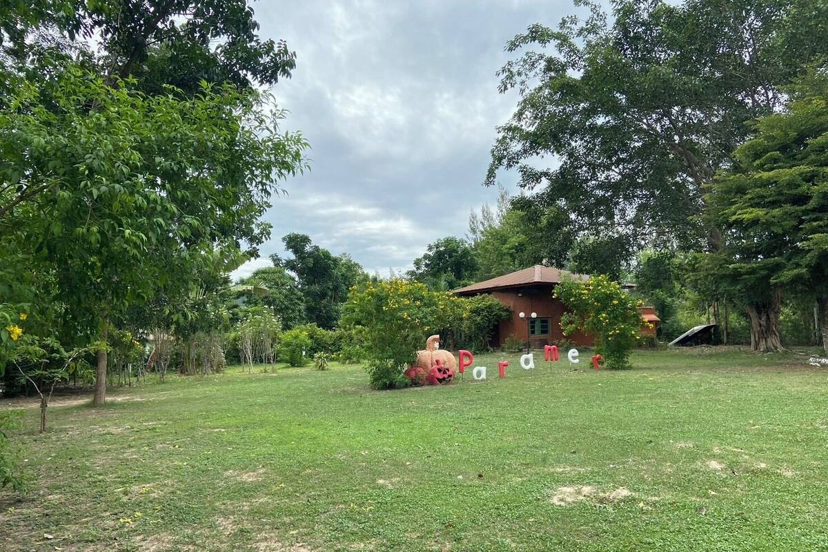 A grassy area with a small brick building and trees.