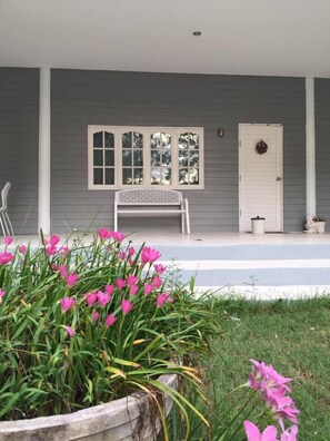 A porch with a bench, a door, and a window with multiple panes.