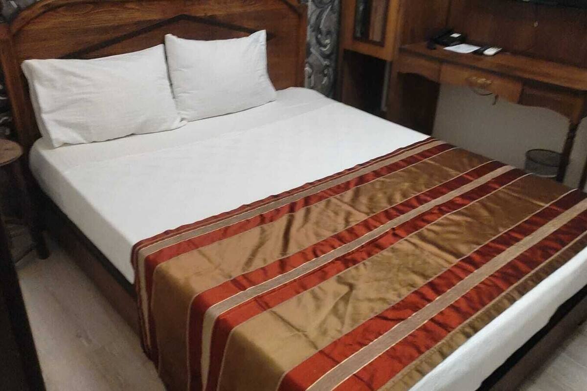 Een bed met een wit laken en een gestreept dekbed.