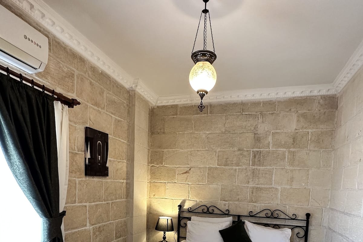 Een slaapkamer met een bed, nachtkastje, lamp en hanglamp.