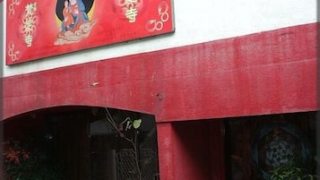A building with a red and white facade, a bicycle parked outside, and various potted plants.