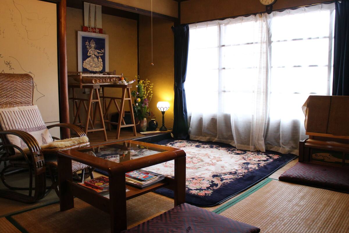 A traditional Japanese-style living room with tatami mats, a low wooden table, and a tatami mat sofa.