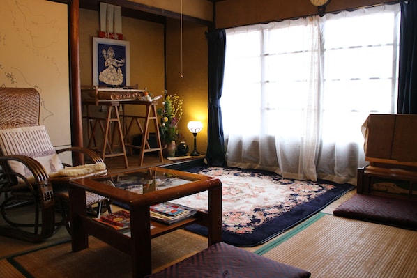 A traditional Japanese-style living room with tatami mats, a low wooden table, and a tatami mat sofa.