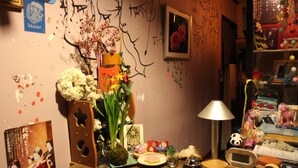 A cluttered desk with various items including a clock, a lamp, and decorative objects.