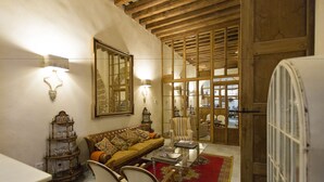 A cozy living room with a sofa, chairs, a coffee table, and a wooden ceiling. - Hotel Casa de las Cuatro Torres (Cádiz)